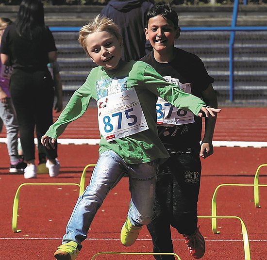 Ein Kind springt beim Hindernislauf über eine Hürde 